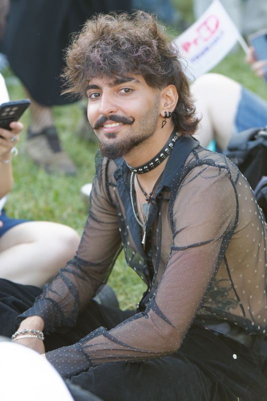9 - Person with a mustache and curly hair wearing a sheer, polka-dot long-sleeve shirt
